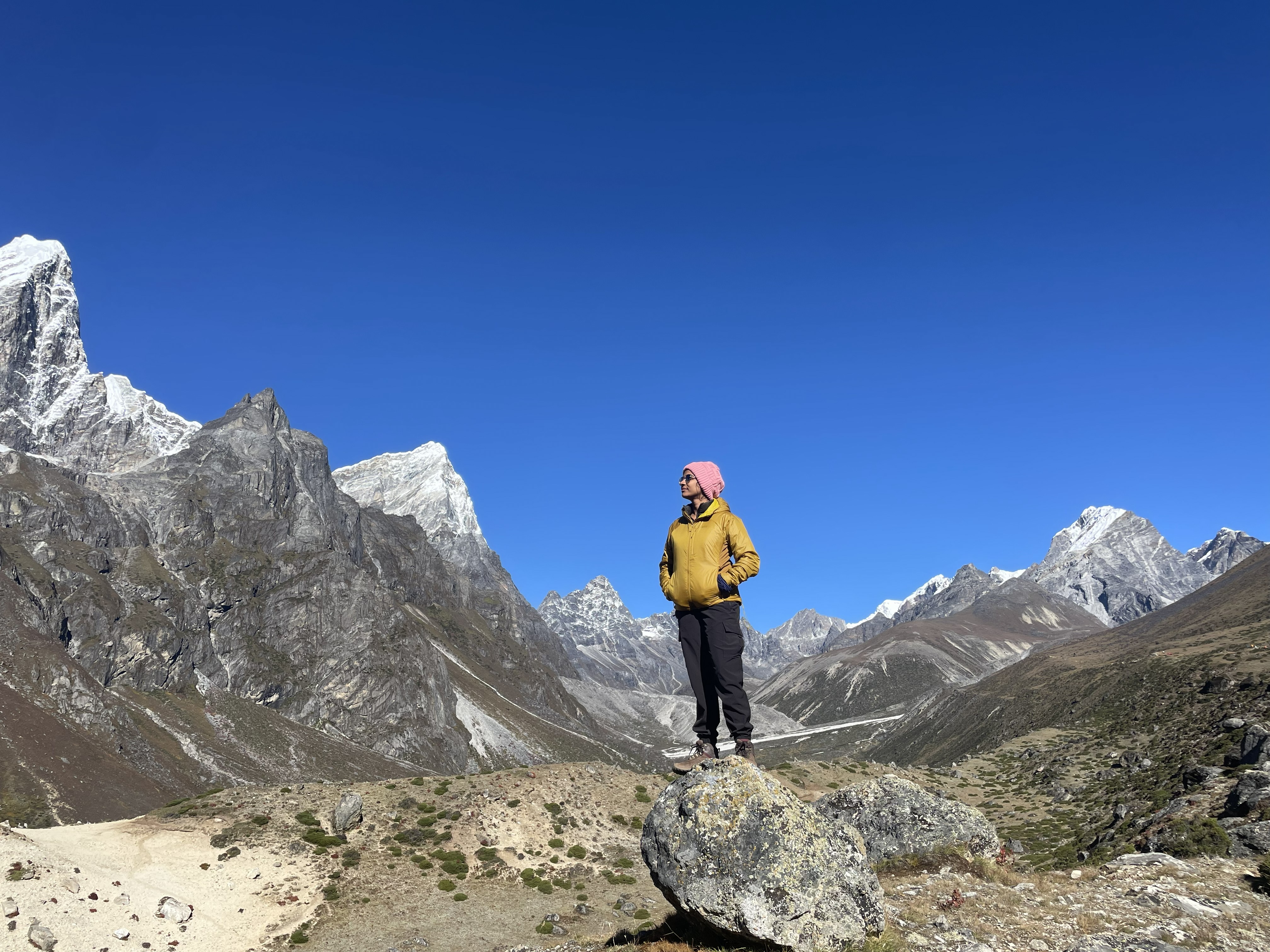 Ujjwala on a rock in the Himalayas, looking out at the valley